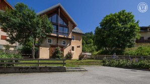 Een gebouw met twee verdiepingen, een groot raam en een houten omheining ervoor.