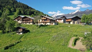 Un ensemble de chalets en bois situés dans une région montagneuse, sous un ciel dégagé.