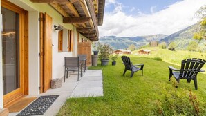 Un chalet doté d’un balcon en bois, d’une terrasse avec des chaises et offrant une vue sur les montagnes.