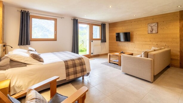 Une chambre d’hôtel moderne équipée d’un lit, d’un canapé, d’une télévision et d’un mur en bois.