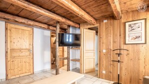 Ein rustikaler Innenraum mit einer Holzbank, einem Fernseher und Holztüren.