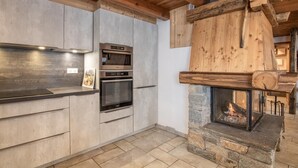 Eine moderne Küche mit integrierten Geräten, einem Kamin aus Stein und Holzbalken.