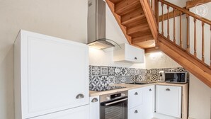 Een kleine keuken met witte kastjes, een magnetron en een ingebouwde oven.
