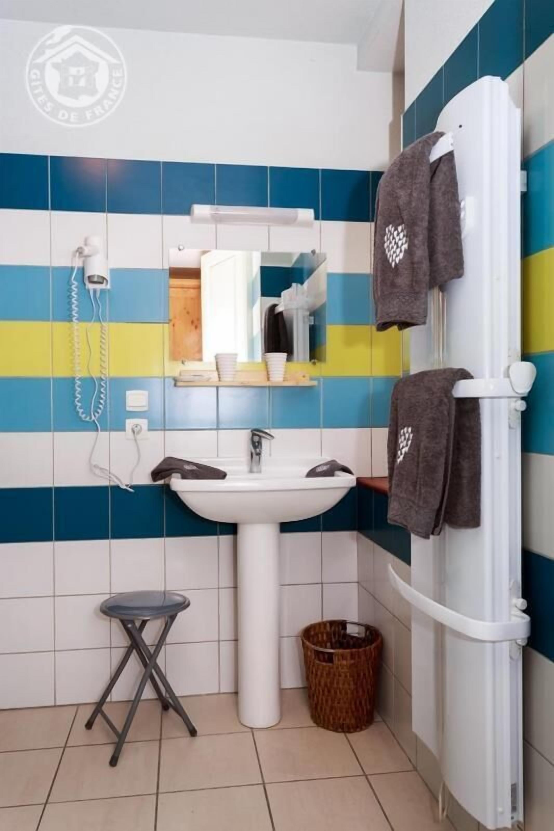 Une salle de bain avec un lavabo blanc, un miroir et un porte-serviettes.