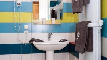 Une salle de bain avec un lavabo blanc, un miroir et un porte-serviettes.