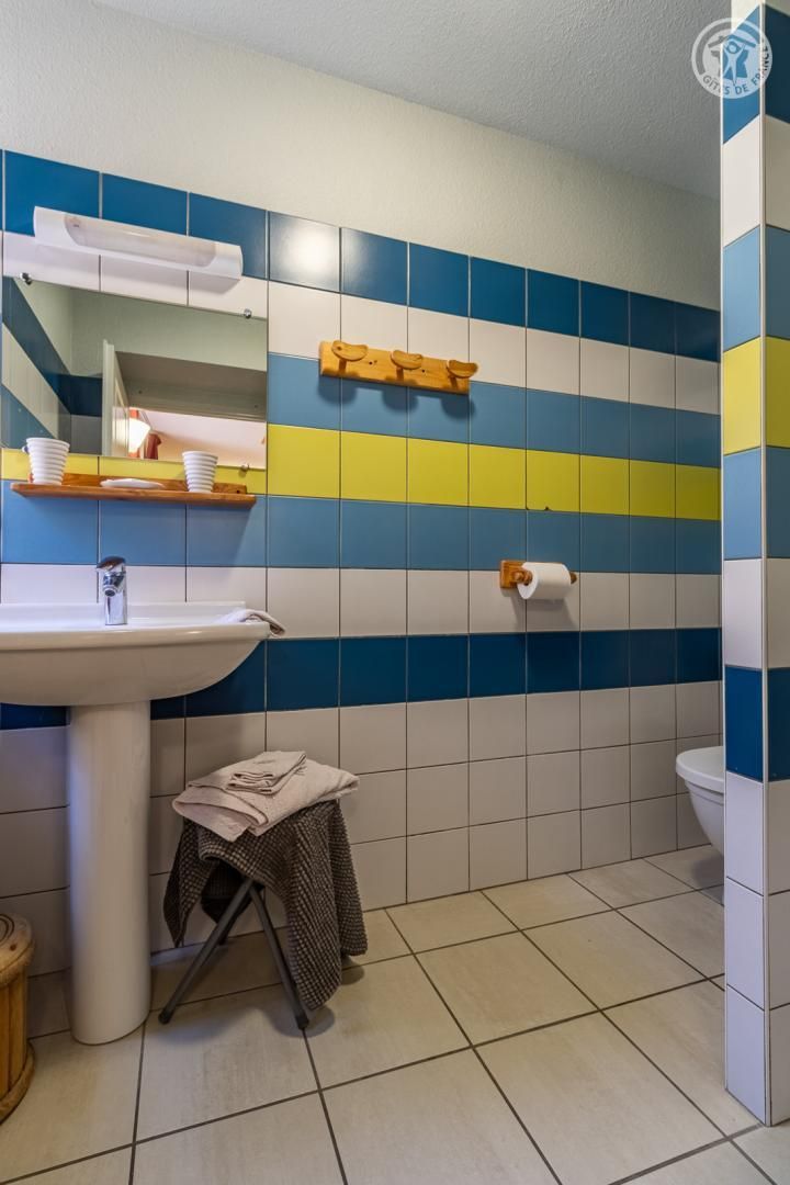 Et badeværelse med vask, toilet og spejl.