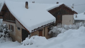 A rustic building with a sloped roof covered in snow, surrounded by a snowbank. - Gite LES Emptes - Aigueblanche (AIGUEBLANCHE)