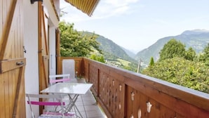 A balcony with a wooden railing, a table, and chairs. - Gite LES Emptes - Aigueblanche (AIGUEBLANCHE)