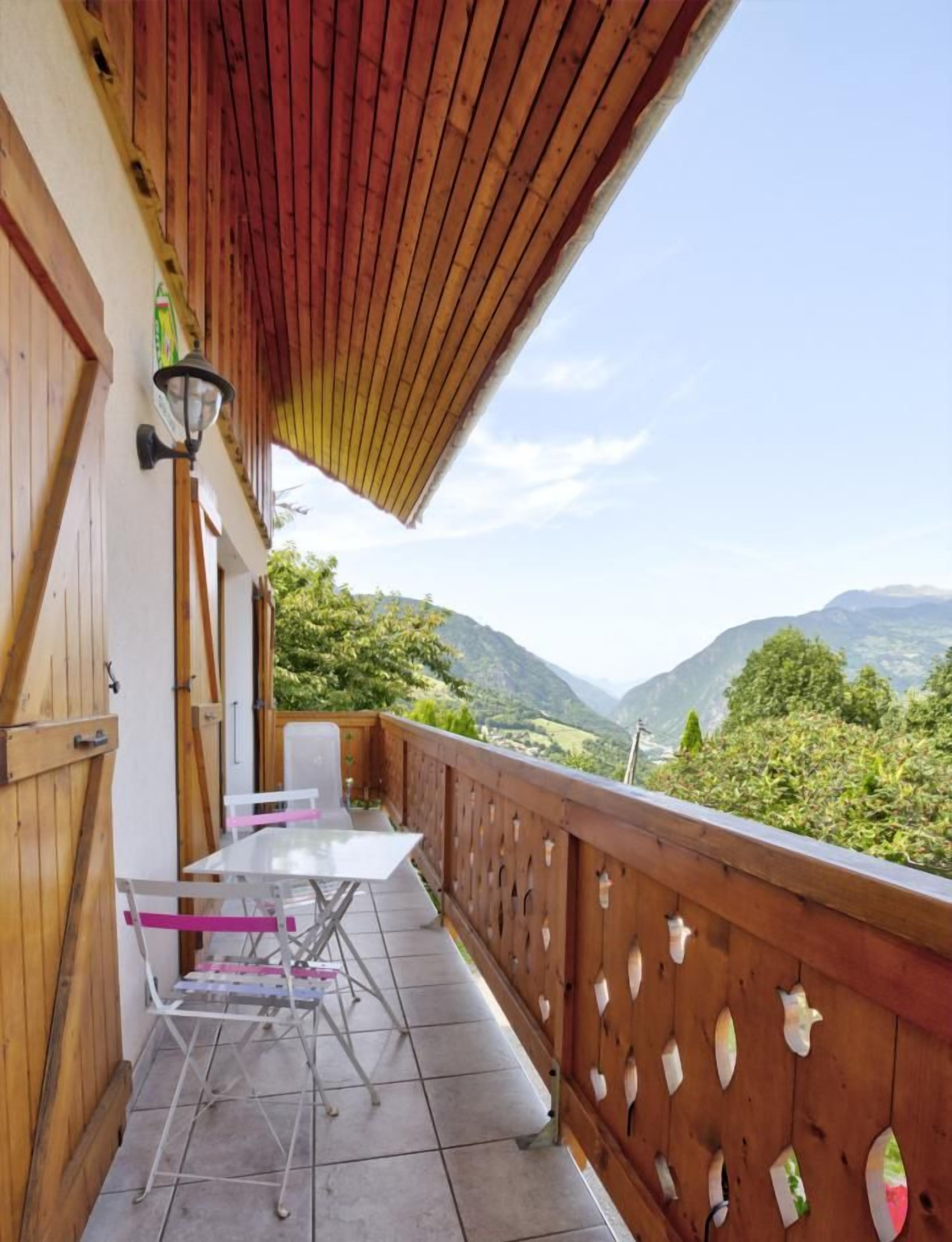 Un balcon avec une balustrade en bois, une table et des chaises.