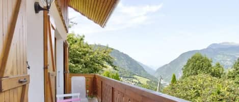 A balcony with a wooden railing, a table, and chairs.