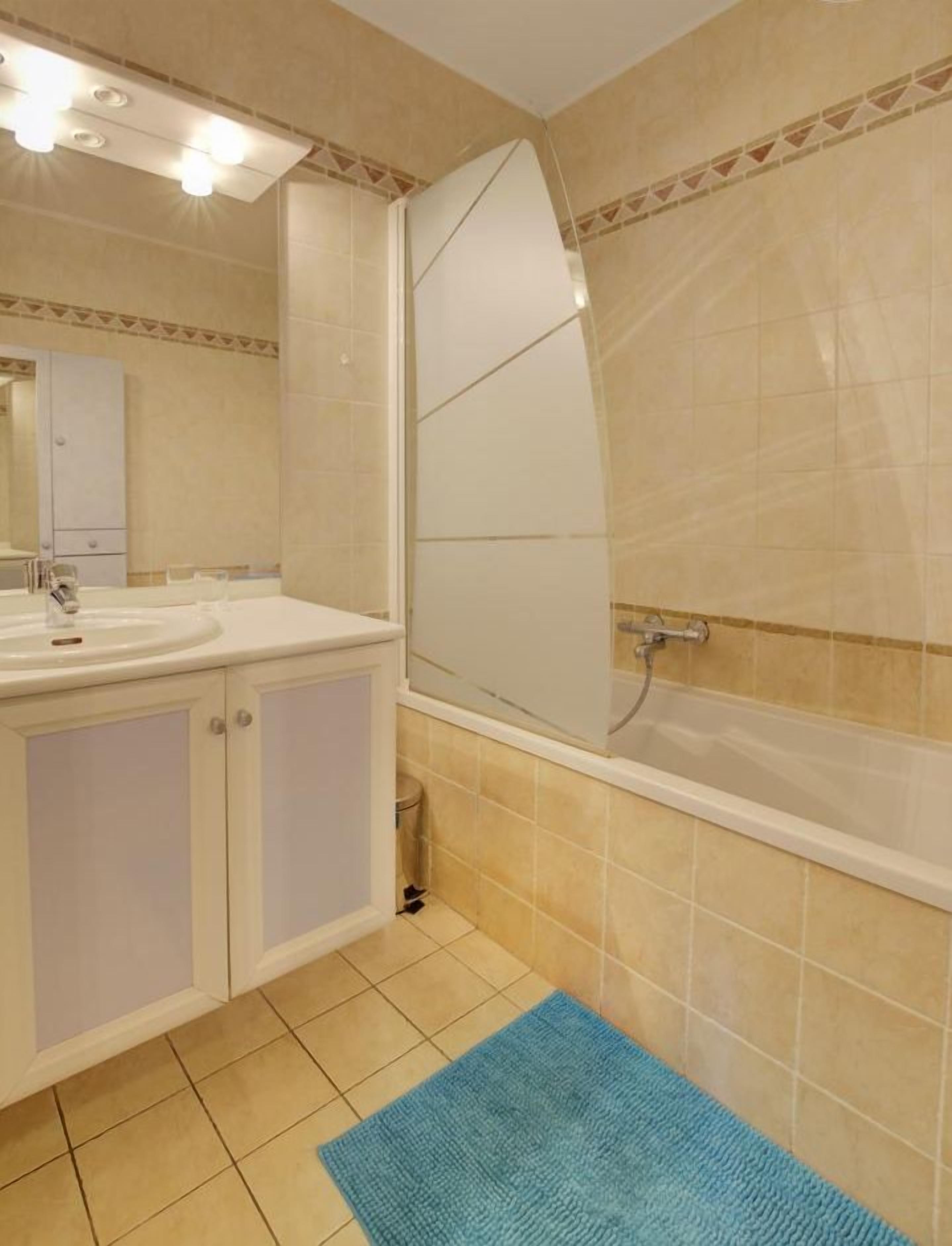 A bathroom with a sink, mirror, and shower.