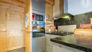 Une cuisine moderne avec des meubles en bois, un réfrigérateur en acier inoxydable et une cuisinière à gaz.