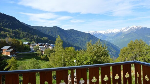 Un village de montagne avec des maisons et une vue sur des sommets enneigés.