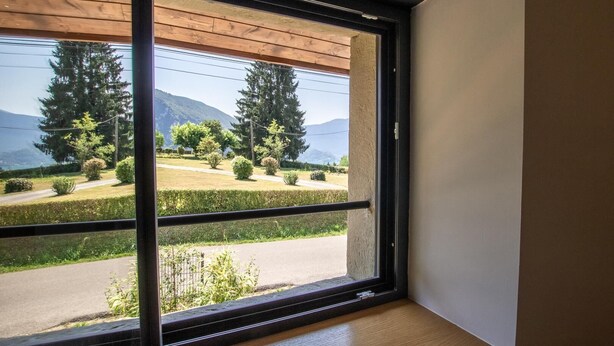 A room with a large window offering a view of a green landscape with trees and a road. - Chez LA Philo - Nances (NANCES)