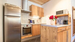 Une cuisine moderne dotée d’appareils électroménagers en acier inoxydable, de meubles en bois et d’un revêtement mural en carreaux.