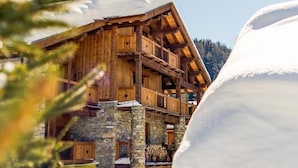 A wooden chalet with stone walls, wooden balconies, and a snow-covered roof. - Chalet Chaudanne - LO Soli (SAINTE FOY TARENTAISE)