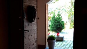 An entrance with a wooden door, a potted plant, and a stone pathway leading outside. - Chalet Chaudanne - LO Soli (SAINTE FOY TARENTAISE)