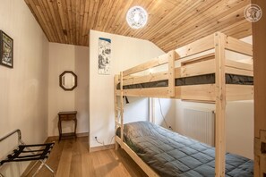 Cozy retreat with a bunk bed, wooden ceiling, and a small table for personal items.