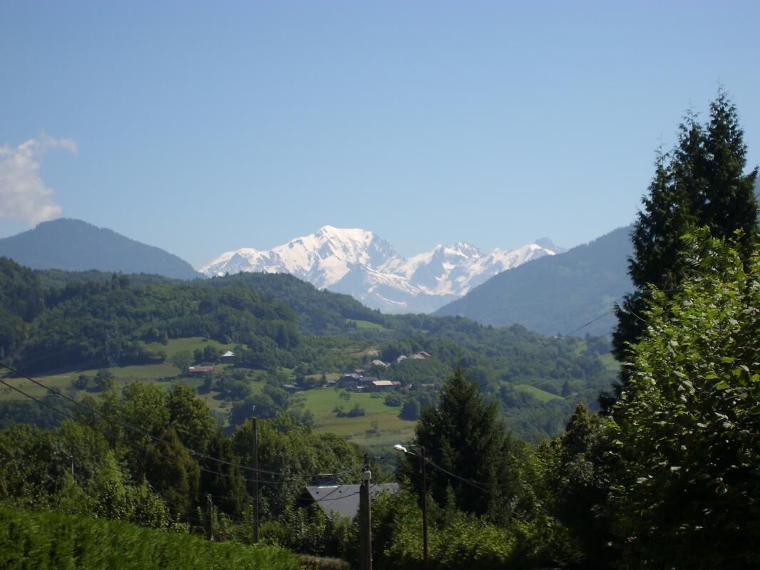 Eine Berglandschaft mit schneebedeckten Gipfeln, saftig grünen Tälern und verstreuten Gebäuden.