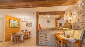 Ein rustikaler Essbereich mit Holztischen und -stühlen, einer Steinsäule und einer Holzbalkendecke.