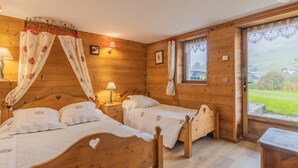 Ein Zimmer mit Holzboden, zwei Betten, einem fenster mit Vorhängen und einer Lampe auf dem Nachttisch.