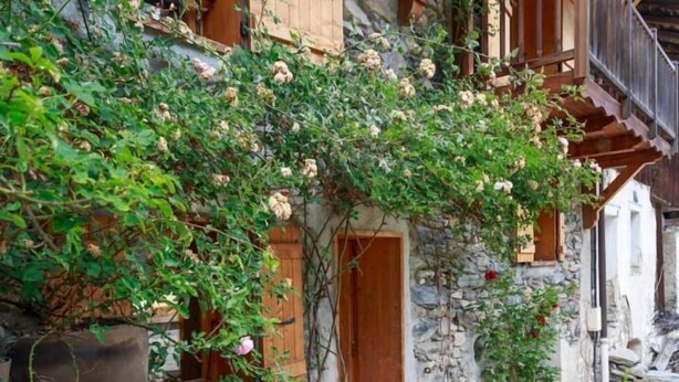 Un edificio rústico de piedra con balcones de madera y un camino de piedras.