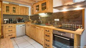 Una cocina con armarios de madera, lavavajillas, estufa y microondas.