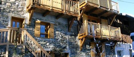 A stone building with wooden balconies and a staircase leading to the entrance.