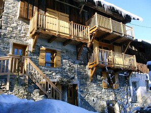 A stone building with wooden balconies and a staircase leading to the entrance.