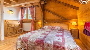 Una habitación acogedora de madera con una cama, dos lámparas de noche y una ventana con cortinas.