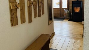 A cozy room with a wooden bench, a fireplace, and a wall adorned with wooden panels. - Chalet LE Char - Gite "LE Plan" (LA GIETTAZ)