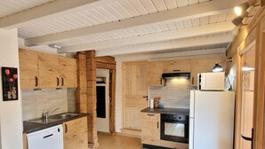 A compact kitchen with wooden cabinets, a dishwasher, a stove, and a refrigerator. - Chalet LE Char - Gite "LE Plan" (LA GIETTAZ)