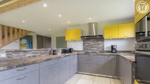 Une cuisine moderne avec des meubles gris, un plan de travail en bois et un mur d’accent jaune.