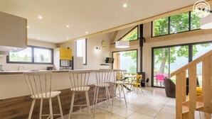Une cuisine moderne dotée d’un îlot central, de tabourets de bar et d’un coin repas avec des chaises jaunes.