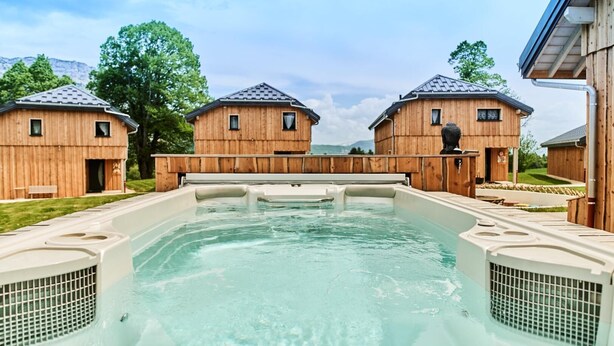 Un espace avec des bains à remous, avec des cabanes en bois en arrière-plan.