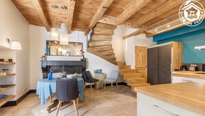 A modern kitchen with wooden accents, a dining area with a table and chairs, and a staircase leading to another level. - Clos DES Platanes-cote Figuier (BRISON SAINT INNOCENT)