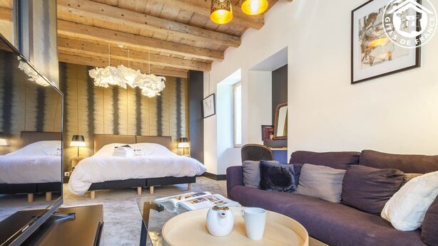A modern hotel room with a large bed, a sofa, a round coffee table, and a mirror. - Clos DES Platanes-cote Figuier (BRISON SAINT INNOCENT)