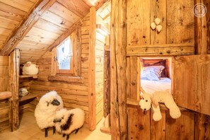 Una cabaña rústica de madera con un altillo y habitación, estantes de madera con juguetes suaves, y un interior acogedor.