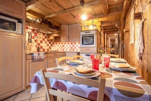 Una cocina rústica y acogedora con armarios de madera, salpicadero a cuadros y una mesa de comedor preparada para cuatro comensales.