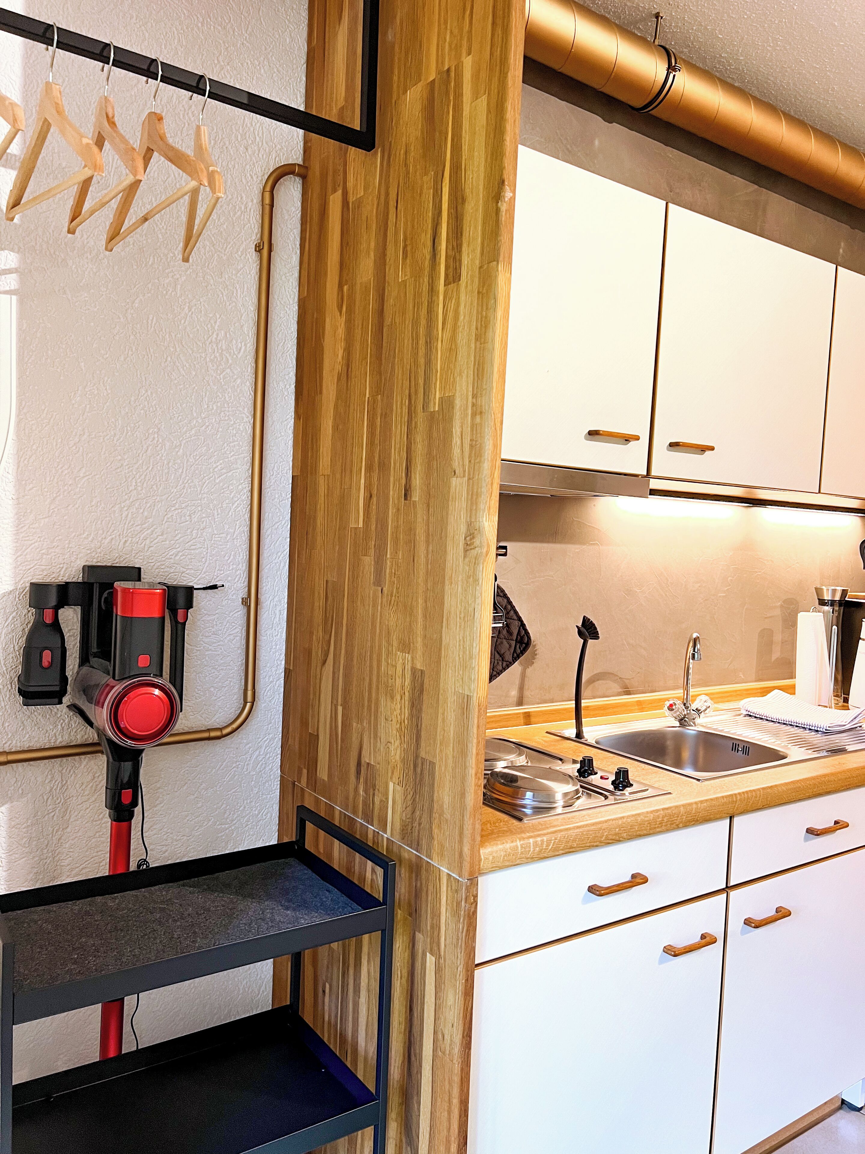 Eine moderne Küche mit weißen Schränken, einer Edelstahl-Spüle und einer Wand mit Holzakzenten.