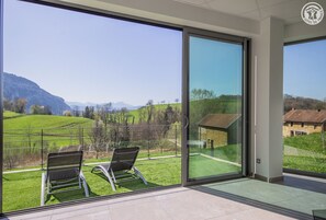 Una habitación moderna con amplios ventanales que ofrecen vistas a un paisaje verde y montañas.