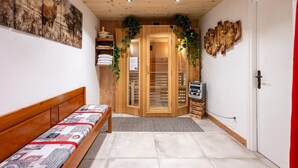 A hotel room with a wooden ceiling, a bed with a patterned bedspread, a wooden wardrobe, and a door with a mirror and a small plant. - L'attrape-rêves - Bessans (BESSANS)