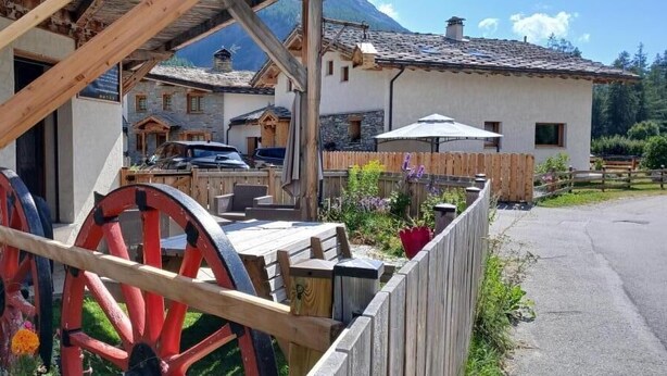 A rustic wooden building with a stone facade, a wooden deck, and a wooden fence. - L'attrape-rêves - Bessans (BESSANS)