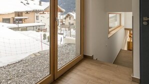 A spacious room with large windows, a wooden floor, and a view of a snowy landscape.