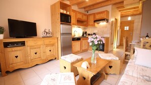 A cozy kitchen with wooden cabinets, a refrigerator, and a dining area with a table and benches. - Chez Marie - Albiez Montrond (ALBIEZ MONTROND)