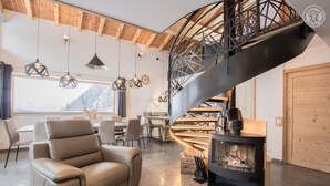 Una sala de estar moderna con una escalera espiral, un sofá de cuero, un comedor y una chimenea.