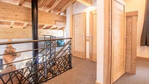 Interior de madera con una escalera, una tubería negra y puertas de madera.