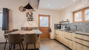 Una cocina moderna con encimera de mármol, armarios de madera y una lámpara colgante.