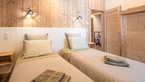 Un dormitorio acogedor con dos camas, paredes de madera y un armario de madera.