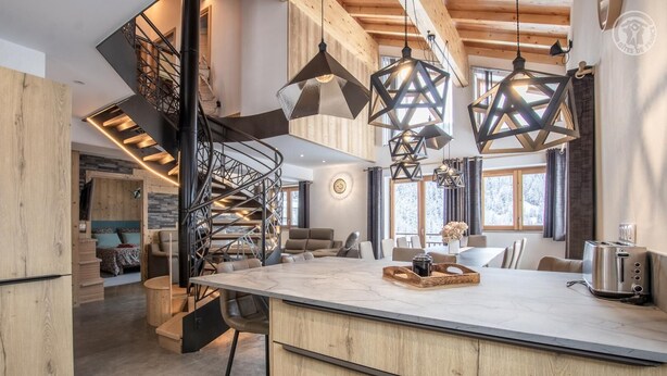 Una cocina moderna con una isla central, muebles de madera y una escalera en espiral.